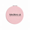 A round pink compact mirror with black text logo